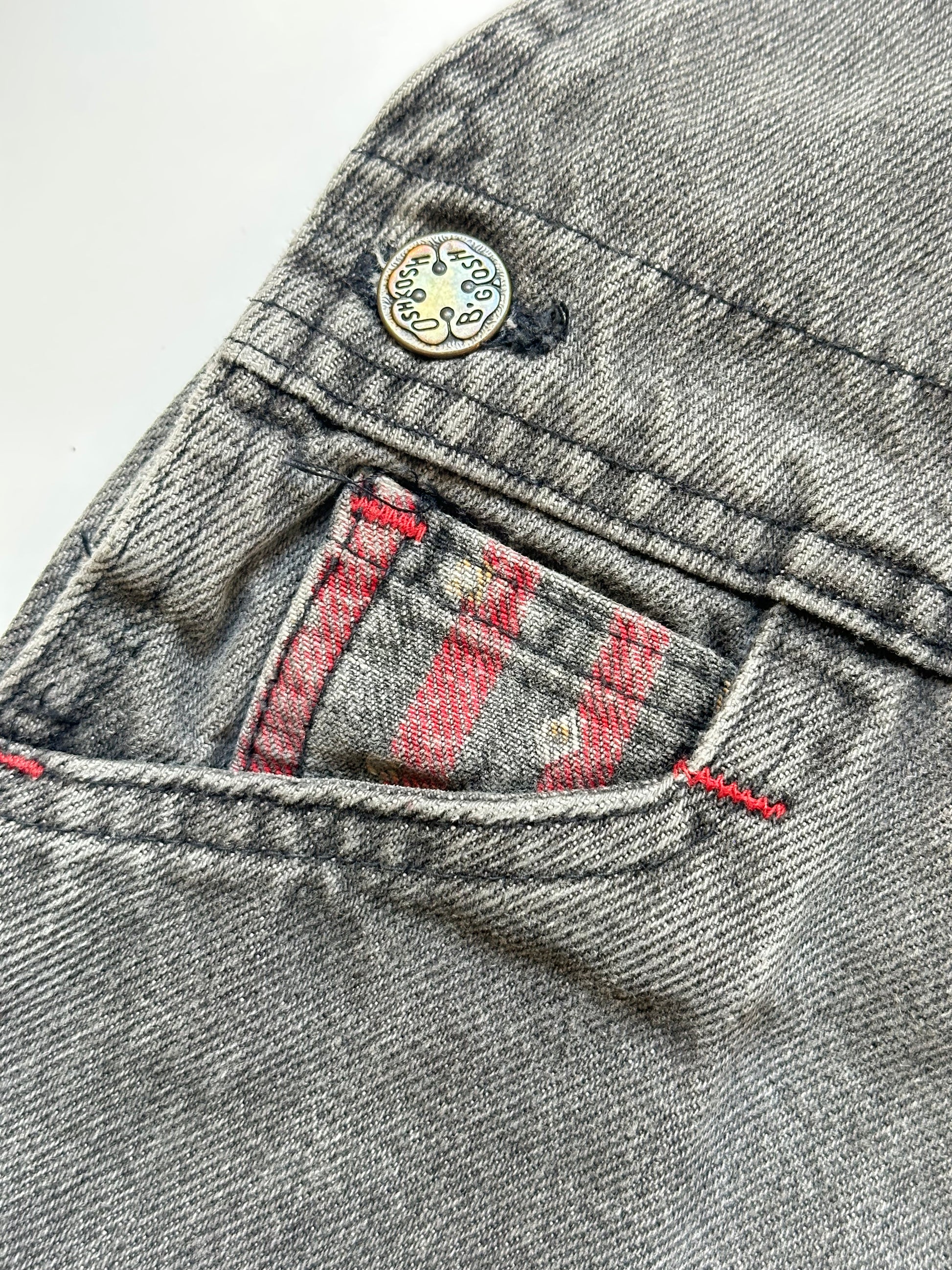 Kids vintage Grey and red denim dungarees with striped straps and Oshkosh brand label on a white background