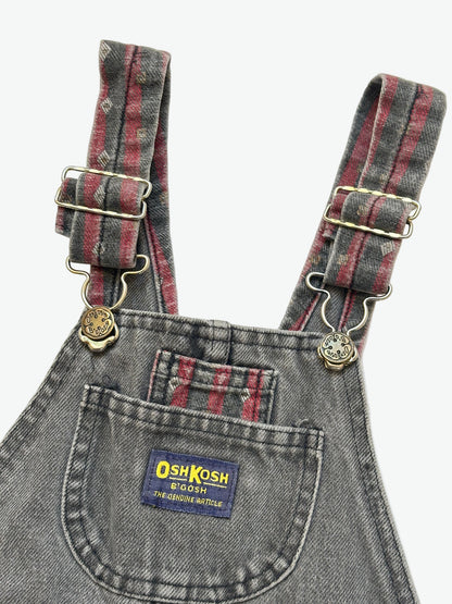 Kids vintage Grey and red denim dungarees with striped straps and Oshkosh brand label on a white background