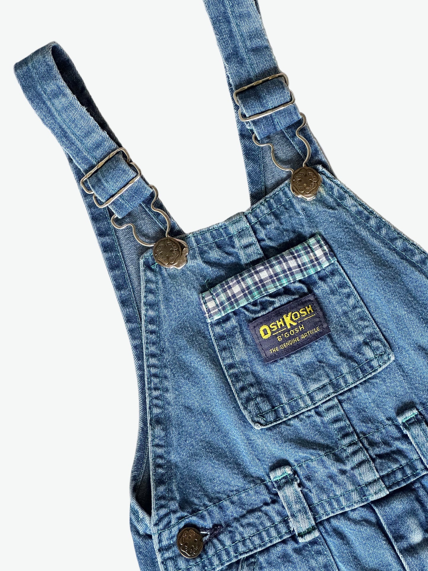 Kid vintage Oshkosh Blue denim dungarees with plaid cuffs and details on a white background