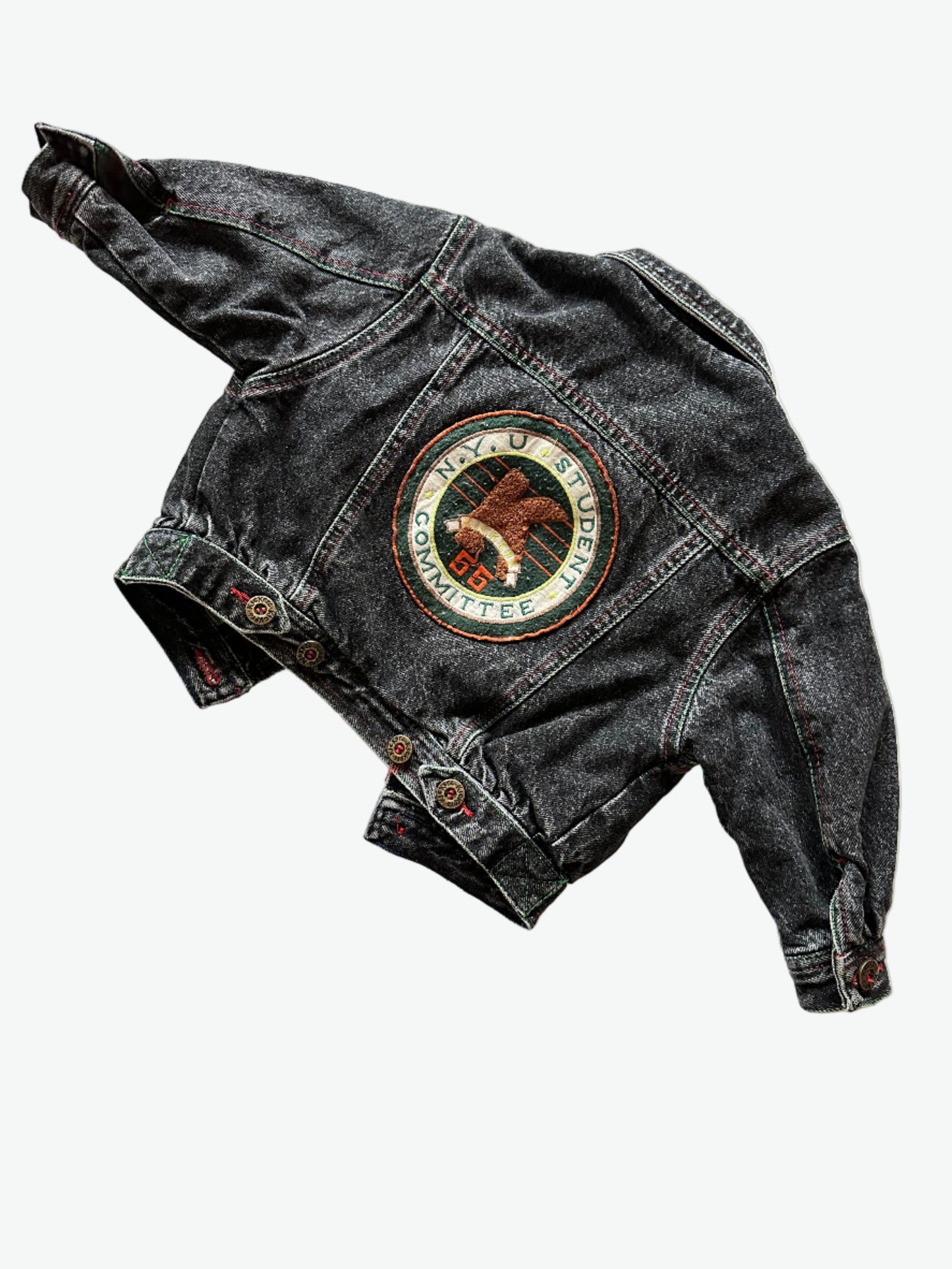 Kids vintage faded black Denim jacket with red stitching, brass buttons and a circular badge on the back on a white background