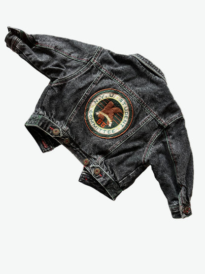Kids vintage faded black Denim jacket with red stitching, brass buttons and a circular badge on the back on a white background