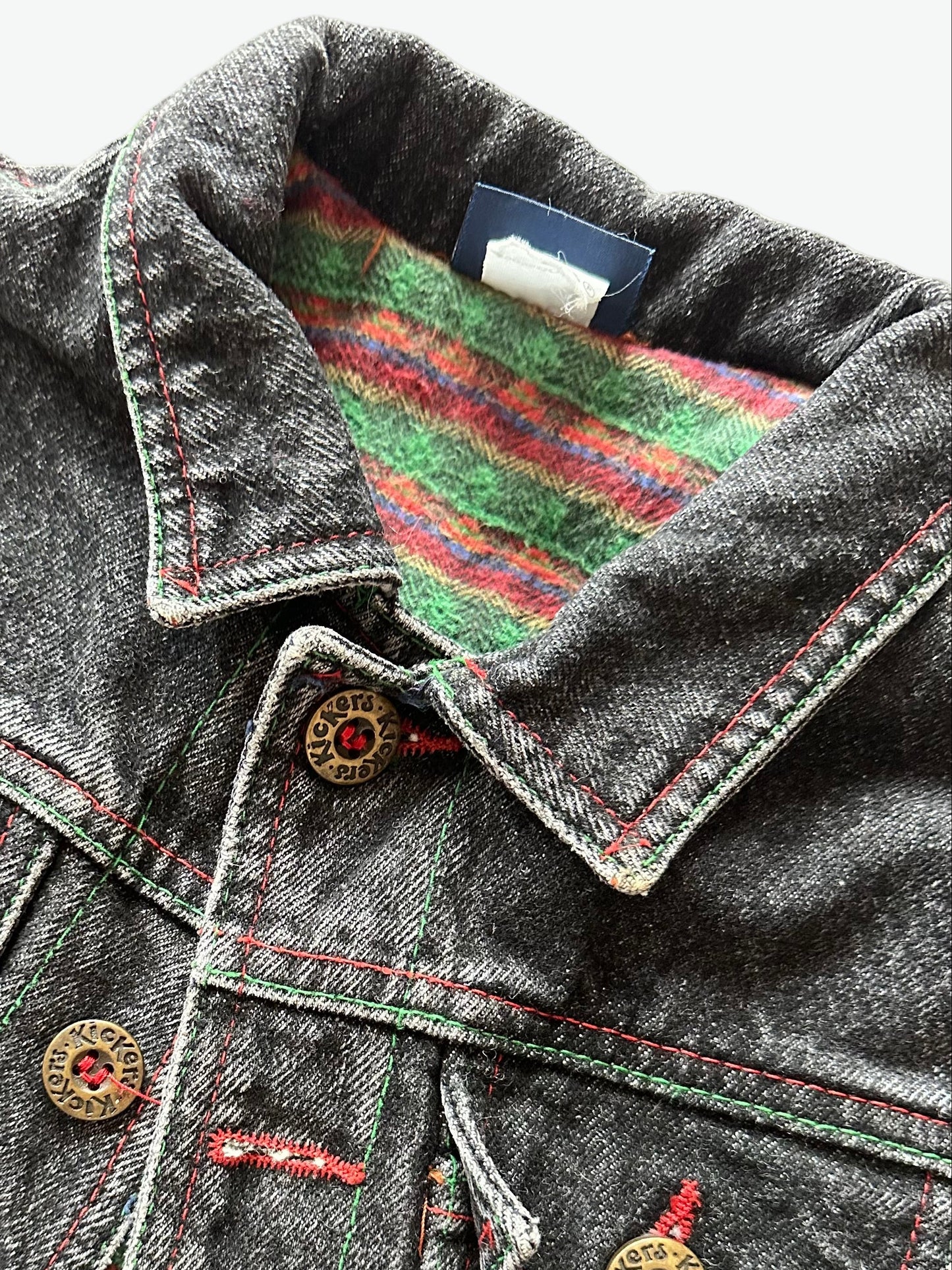 Kids vintage  faded black Denim jacket with red stitching, brass buttons and warm checkered lining on a white background
