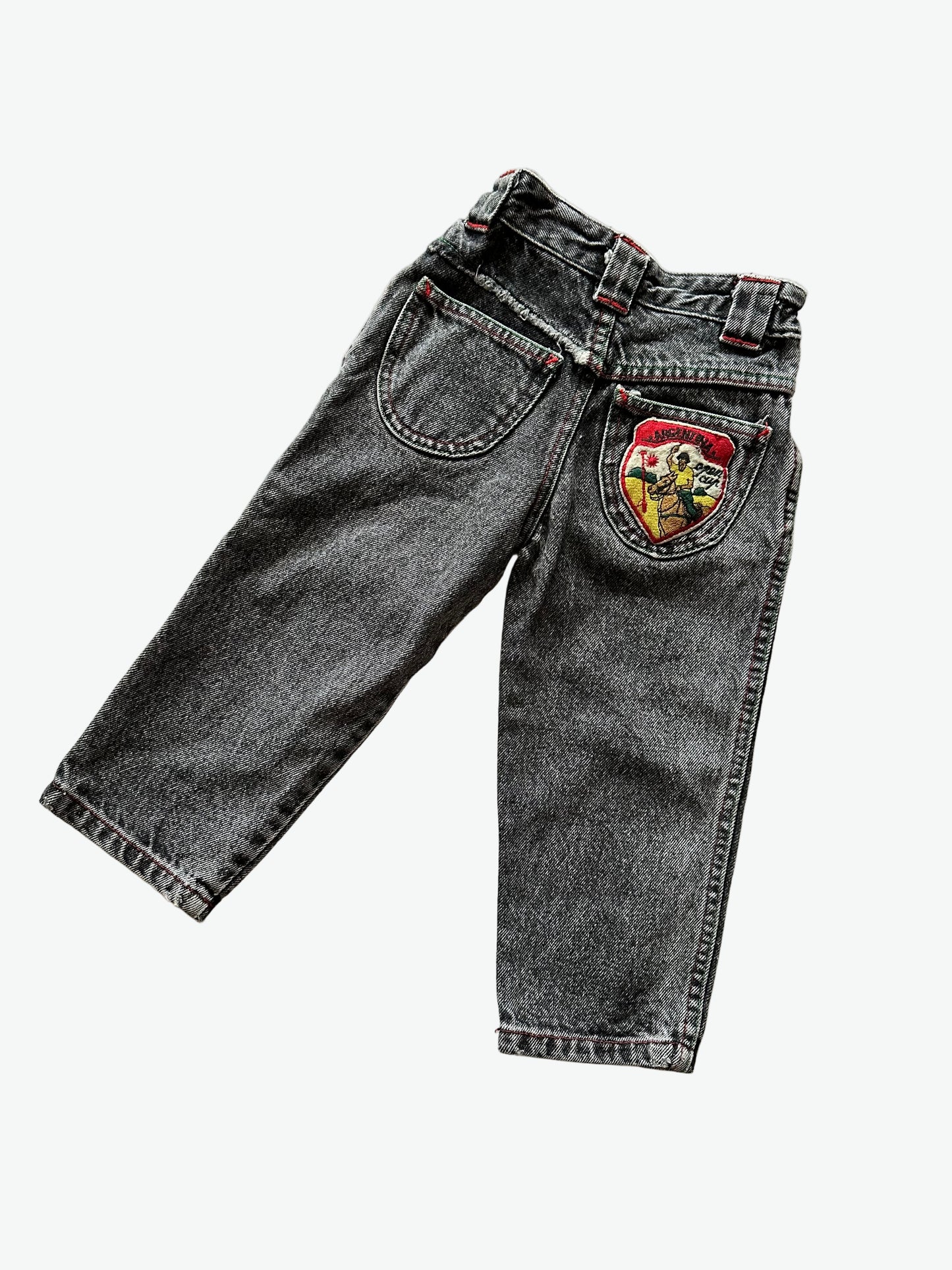 Kids vintage faded black denim jeans with a colourful patch featuring a graphic design and text.