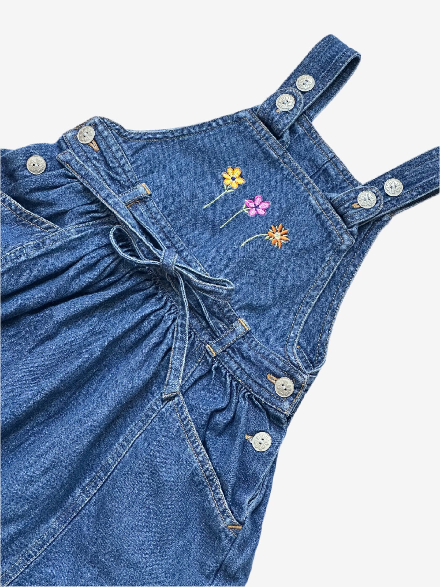 Kids vintage Denim Dress from British brand Adams from the 90s. Adjustable button strap closure with a full a-line skirt perfectly girly with simple flower embroidery at the front, flower embossed buttons and tie.Age 18-24 Months.