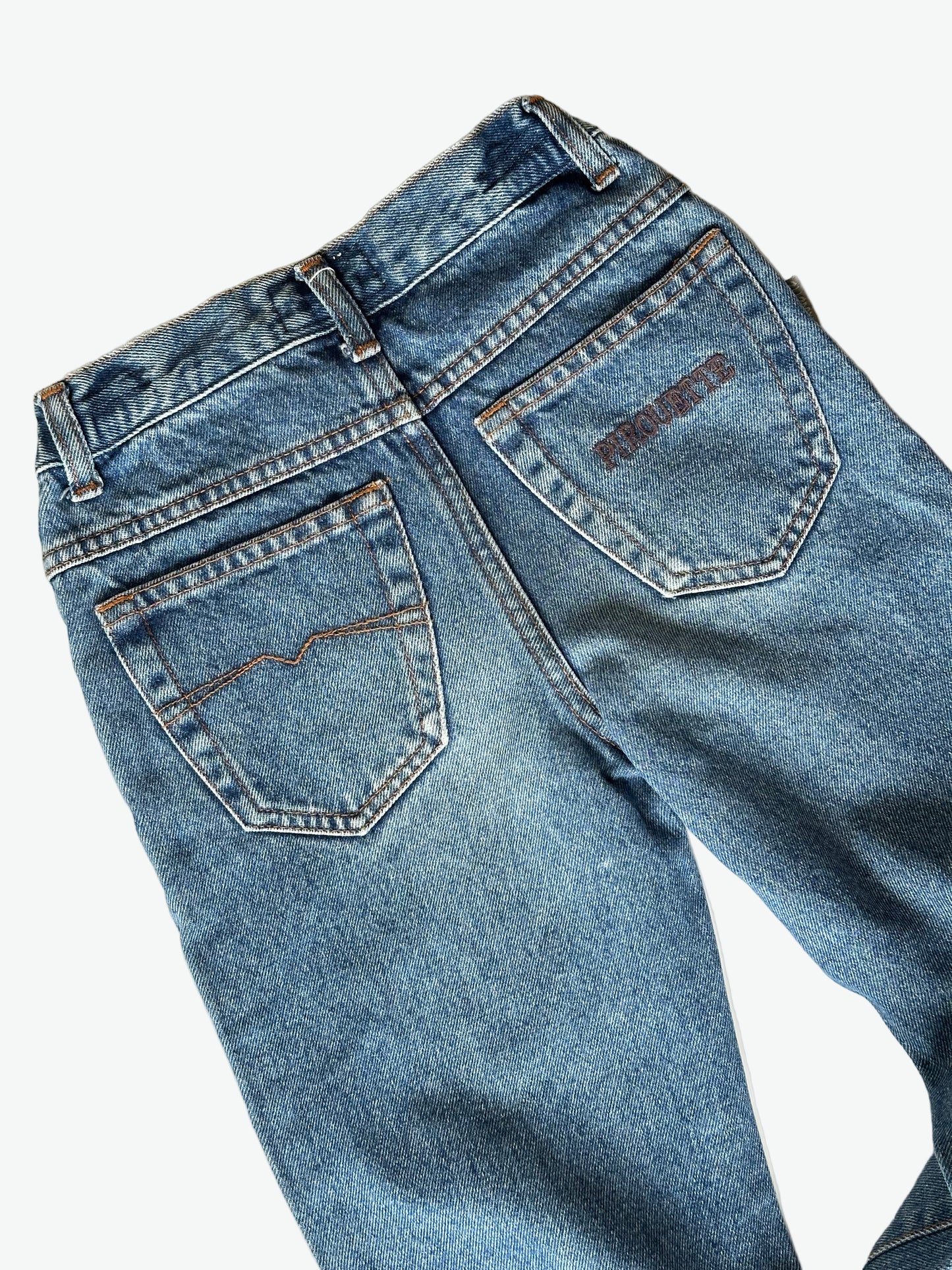 Pair of authentic blue jeans with silver hardware and back pocket embroidery on a white background