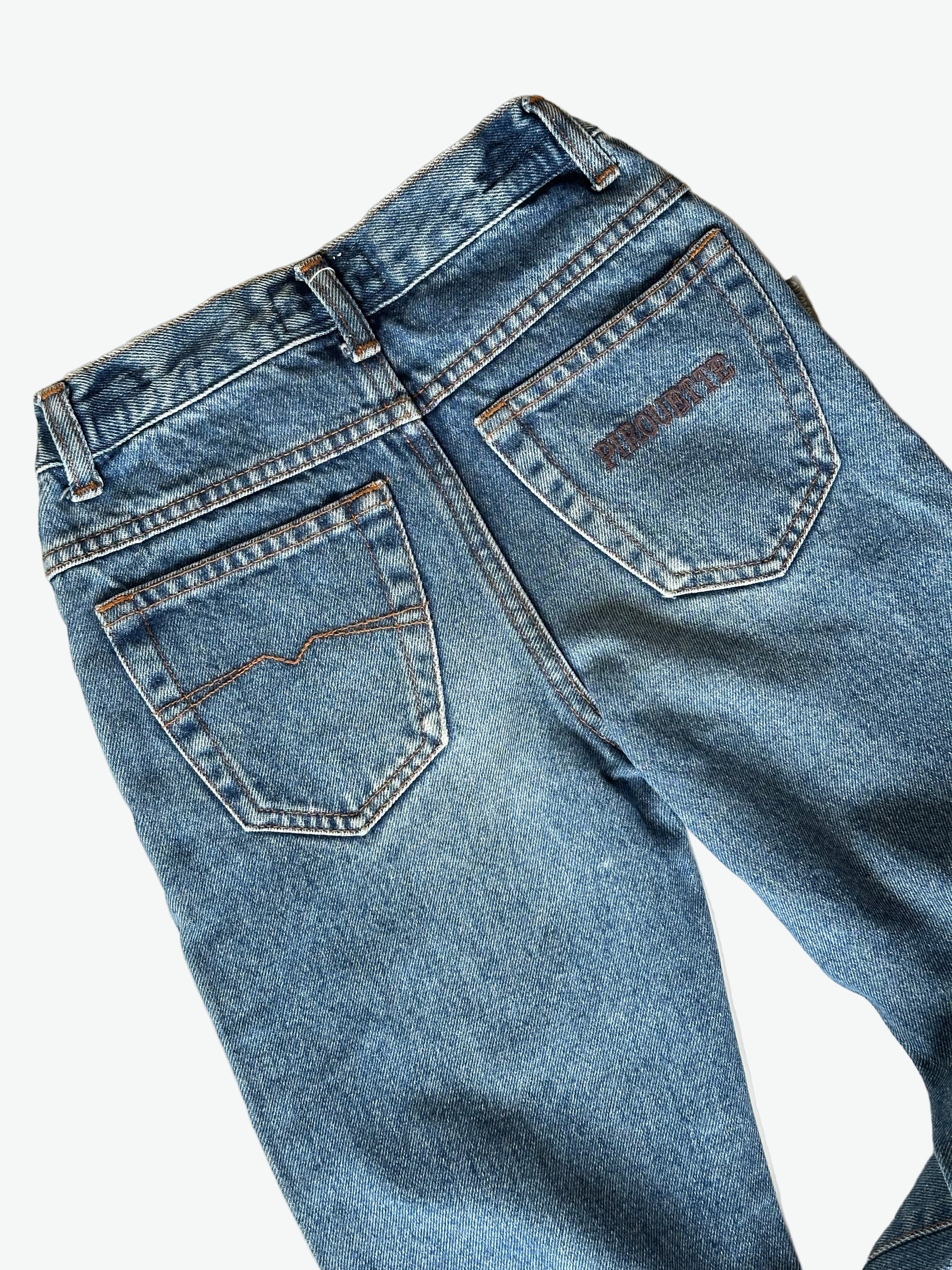 Pair of authentic blue jeans with silver hardware and back pocket embroidery on a white background
