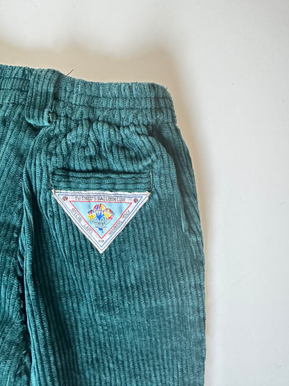 Dark green corduroy pants with a triangle label on a light background