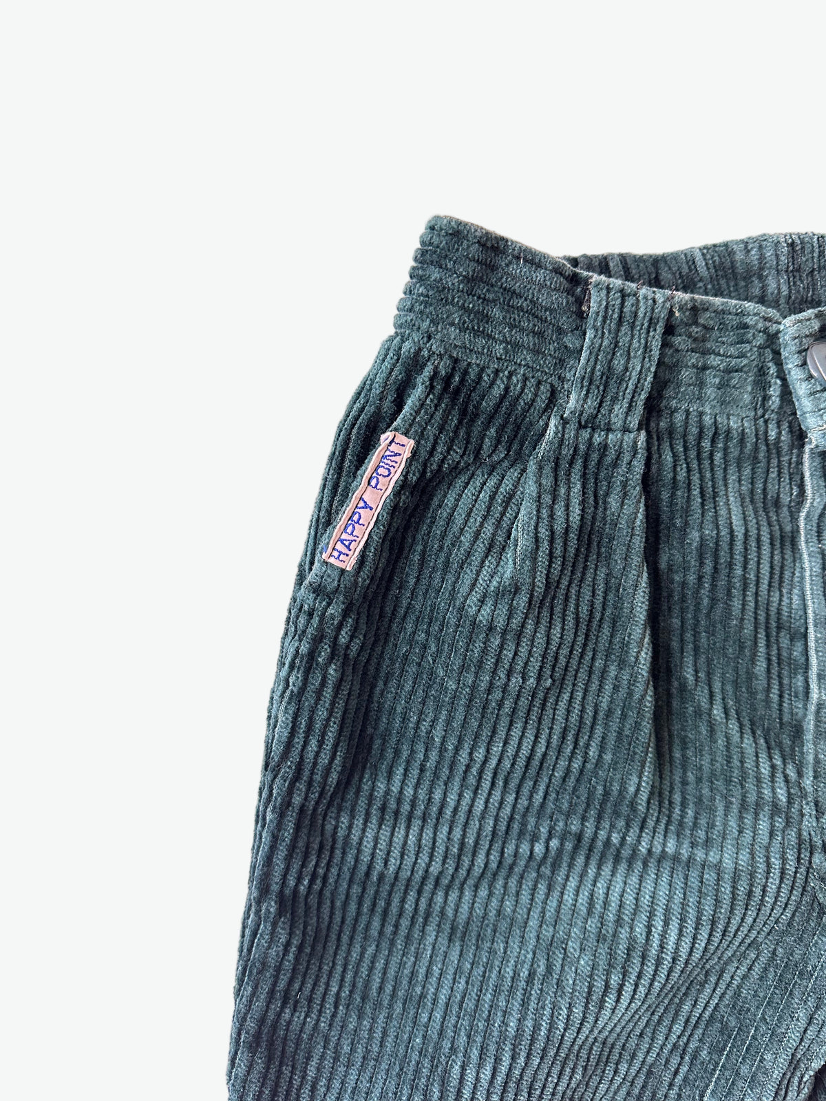 Close-up of dark green corduroy pants with a brand label on a white background