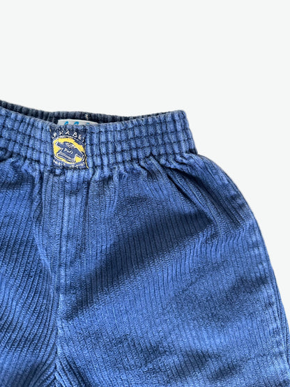 Close-up of inky blue corduroy pants with a brand logo on a white background