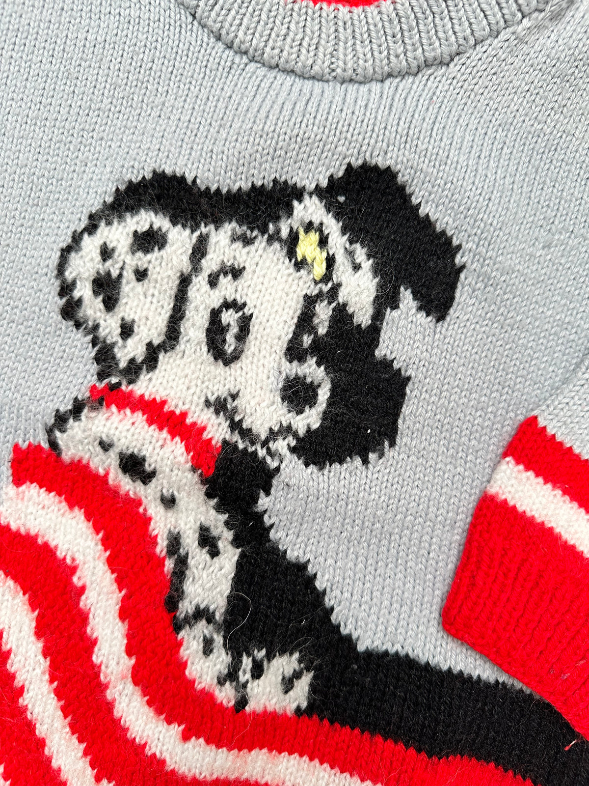 Grey Hand knitted 101 Dolmatians jumper with red and white pattern on a light gray background.