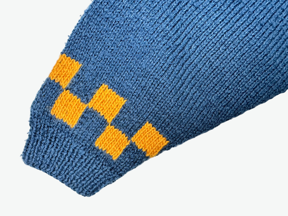 Blue knitted jumper with yellow pattern on a light gray background