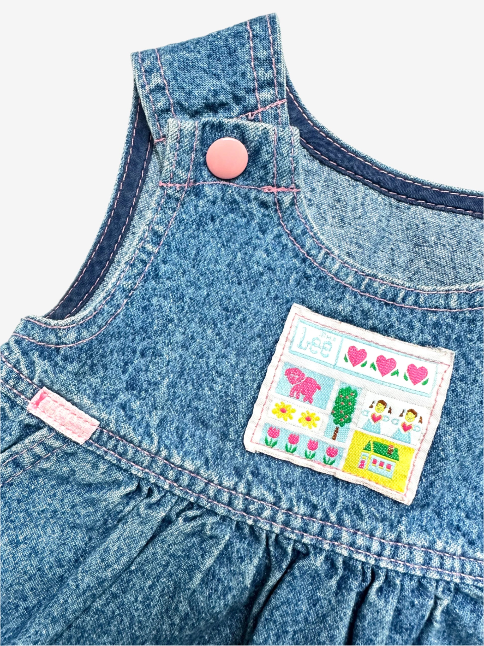Kids Vintage acid wash dress from denim brand Lee, made in U.S.A, features an adorable chest badge featuring hearts, flowers, a tiny house, and a dog to the sweet pink enamelled popper fastenings on the straps. The A-line shape with gentle gathering at the waist makes it comfy and easy to wear. Age 2 years.