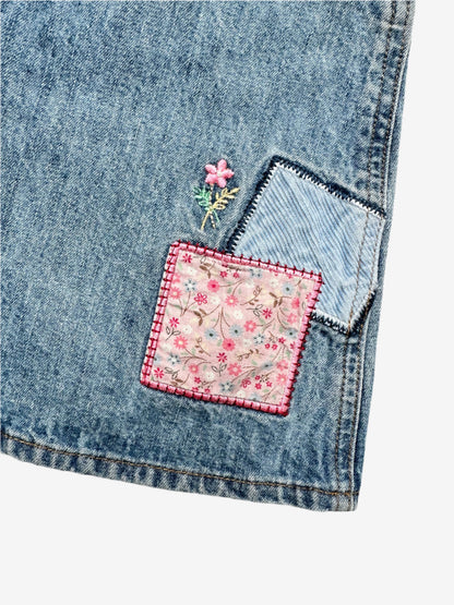 Kids vintage OshKosh dungaree dress, featuring ditsy floral lining inside the top, delicate embroidered flowers, and playful patch details. Mid-wash denim with classic OshKosh branding, it’s finished with antique brass trimmings and sturdy dungaree buckles. Age 4 years.