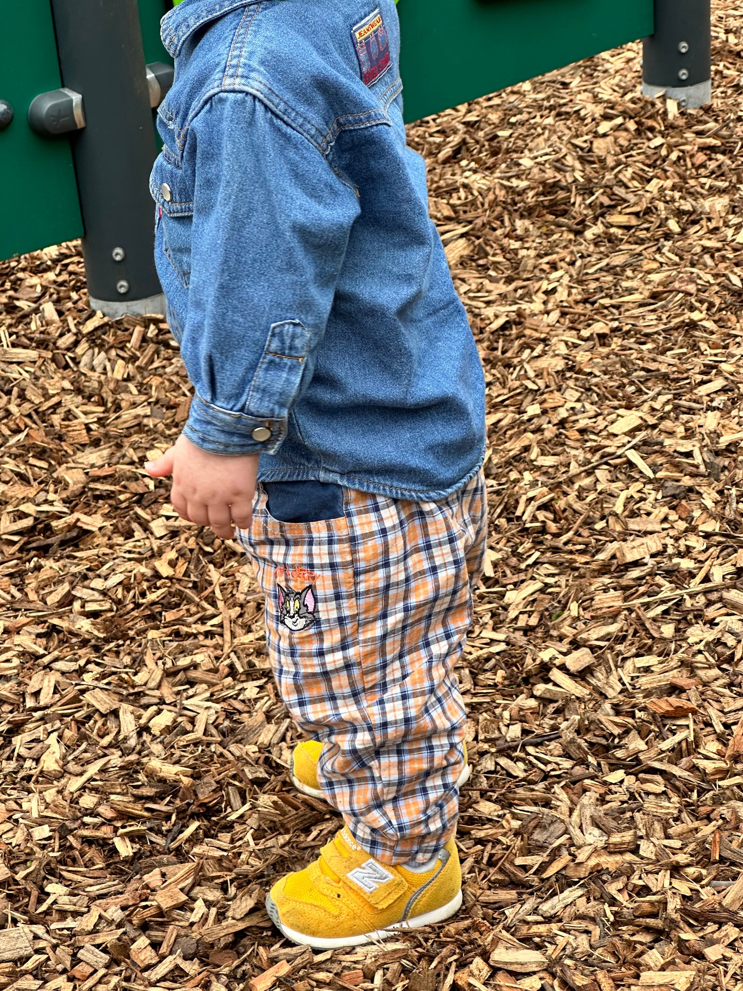 KIDS VINTAGE OUTFIT DENIM SHIRT CHECKT TROUSERS, WORN IN THE PARK WITH YELLOW TROUSERS, BACKGROUND IS BARK ON THE FLOOR. AGE 18 MONTHS