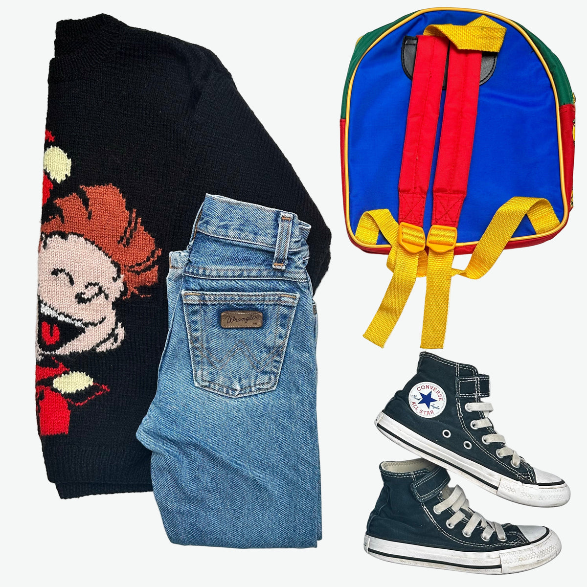 Kids vintage outfit - Black sweater with cartoon character, blue Wrangler jeans, black converse trainers, and colourful backpack on a white background