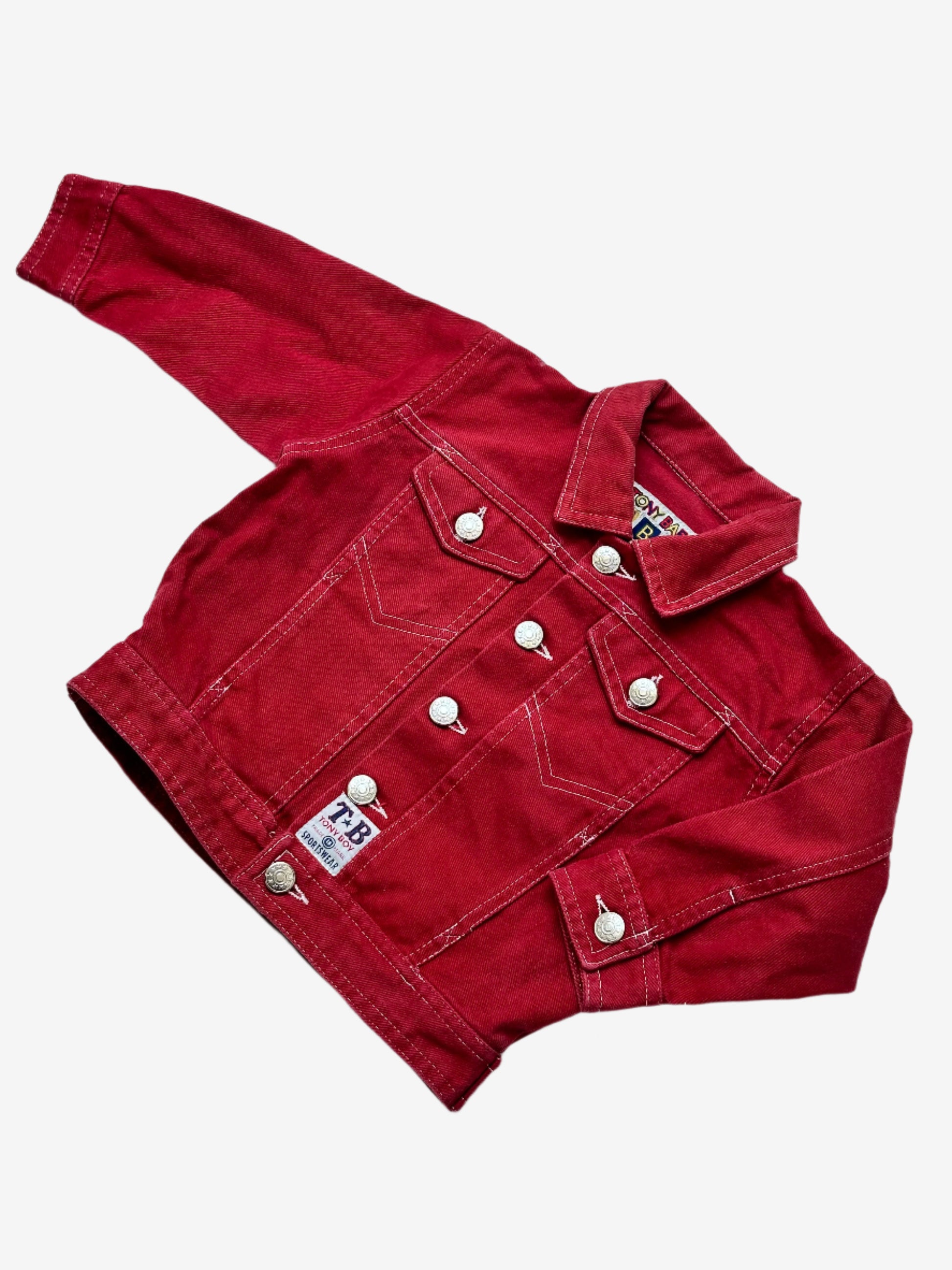 KIDS VINTAGE RED DENIM JACKET WITH SILVER BUTTONS AND BADGE DETAILS ON A PLAIN BACKGROUND.