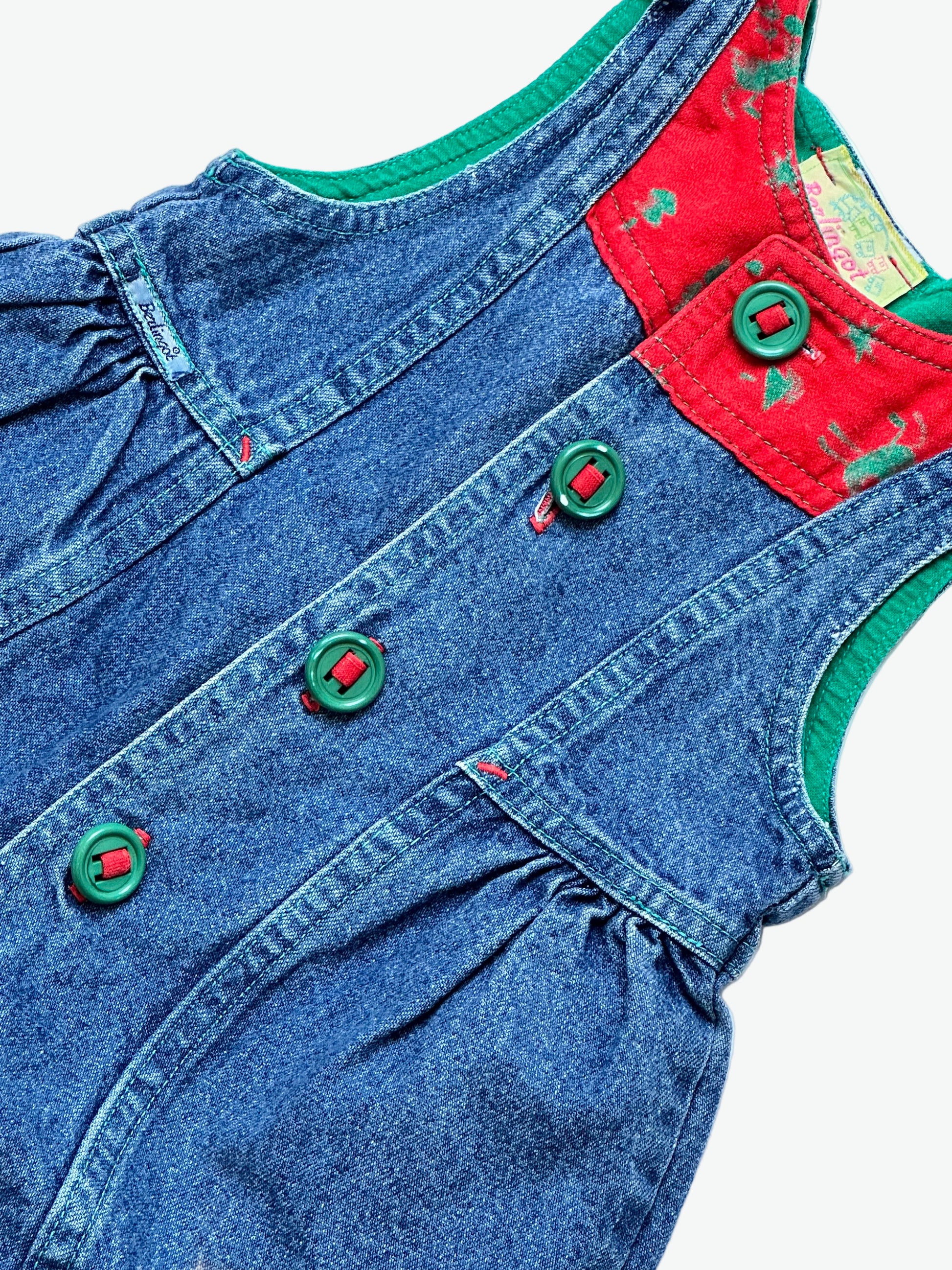 True blue denim romper with red patch detail with festive print and green buttons on a white background