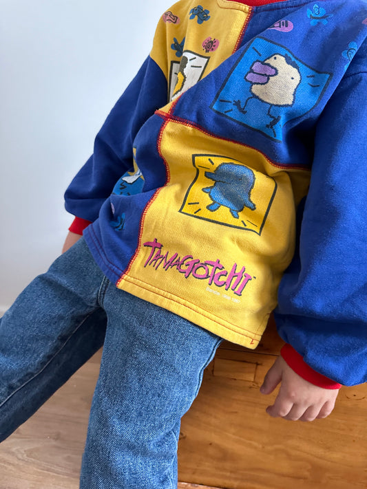 Kids vintage jumper branded Tamagotchi. Multi colour - red, blue and yellow, printed detail from 1996-1997. Age 10 years. 